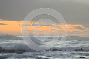 Sunset across rough seas and cloudy skies