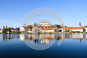 At sunset, the ancient buildings and reflections along the river in Ptuj with blue sky