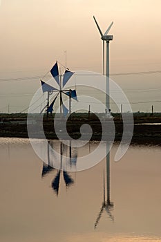 Sunset at ancient and new wind mill use for move the sea water i