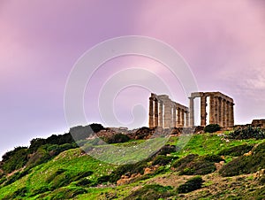 Sunset at Ancient ruins of Poseidon temple under sky with clouds in winter time  in Sounio, Attica, Greece