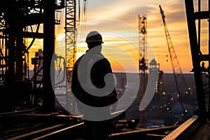 Sunset assessment Engineer man checks project at construction site silhouette