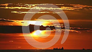 sunset back on dark cloud on the sea and silhouette cargo ship in the summer