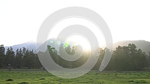 Sunset on the background of trees, rural landscape, green field and mountains. Evening countryside nature landscape