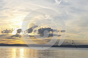 Sunset on Balaton Lake, Hungary. Unrecognizable man wakesurfing in the cable park, on the lake at golden sunset