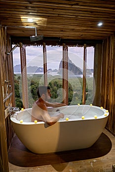 Sunset in bathtub in the bathroom during vacation in Thailand watching sunset over the ocean and moutnains Phangnga Bay photo