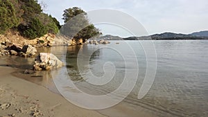 Sunset beach with calm sea, rocks ,and trees