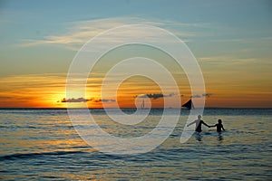 The sunset in the beach with the couple holding hands