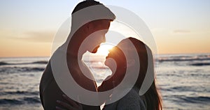 Sunset, beach and couple hug, kiss and share moment at the ocean for bond, freedom or travel. Sunrise, love and