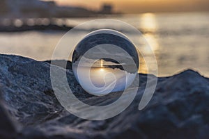 Sunset on the beach with crystal ball resting on the rock. Spain.