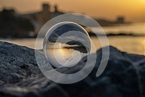 Sunset on the beach with crystal ball resting on the rock. Spain.