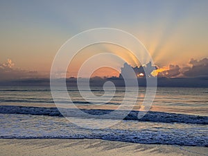 Sunset on the Beach in Florida with Rays of Sunlight Behind Clouds