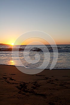 Sunset on the beach with foot prints in the sand