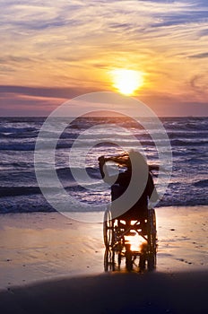 Sunset on the beach handicapped woman in wheelchair