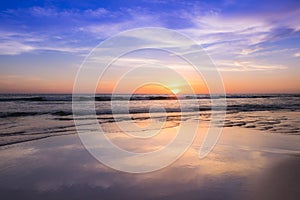 Sunset at the beach with light golden time and the violet sky reflects on the surface