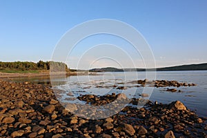 A sunset beach or shoreline full of large rocks on the Strait of Canso between Cape Breton and Mainland Nova Scotia