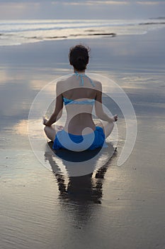 Sunset beach yoga practice in Bali. Lotus pose. Padmasana. Hands in gyan mudra. Meditation and concentration. Zen life. Relaxation