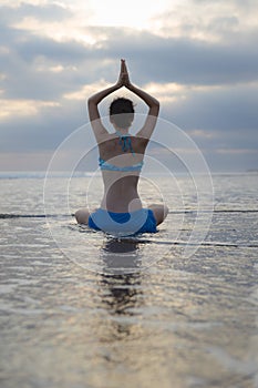 Sunset beach yoga practice in Bali. Lotus pose. Padmasana. Hands in namaste mudra. Meditation and concentration. Zen life. Yoga