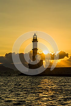 Sunset behind an ancient stone lighthouse Venetian Port, Chania, Crete