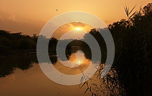 Sunset behind clouds reflecting in a lake in Delhi in India