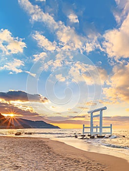 Sunset behind the coast of the Itoshima Beach in Fukuoka whith a white Shinto torii gate in the sea.