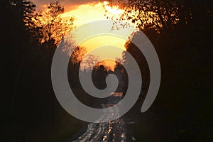 Sunset behind storm clouds along a country road