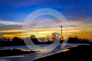 sunset behind the tower and lush trees, on the edge of the lake