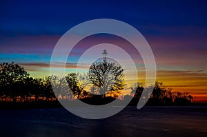 sunset behind the tower and lush trees, on the edge of the lake