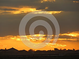 Sunset behind trees with clouds and a road in foreground