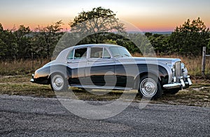 Sunset behind vintage luxery limousine on a Texas country road.