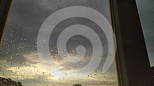Sunset behind windowglass with raindrops.