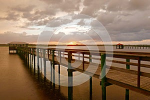 Sunset behind a wooden pier over water