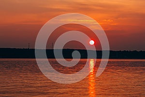 Sunset with big red sun over the water of sea