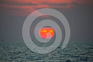 Sunset. Big sun on horizon. Red clouds on the sky. Beautiful seascape. Ocean beach or coast. Florida Gulf of Mexico