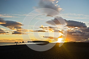 Sunset on black beach with Dyrholaey rock in background,Iceland