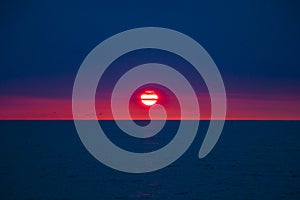 Sunset at the Black sea, big, red sun and blue sea