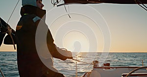 Sunset, boat and man pull anchor at ocean to travel, vacation or holiday outdoor. Tighten rope, sailing and person on
