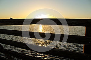 Sunset at bolsa chica wetlands through a wooden bridge photo