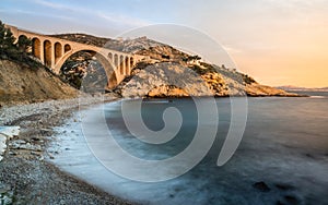 Sunset at Calanque des Eaux Salees or Salt water rocky inlet with Pebble beach and old railway bridge near Marseille France