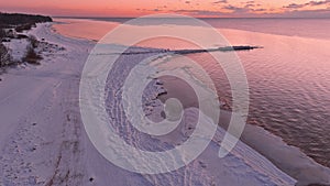 Sunset in a calm sea with frozen seashore.