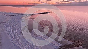 Sunset in a calm sea with frozen seashore.