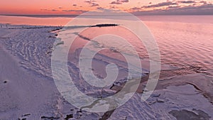 Sunset in a calm sea with frozen seashore.