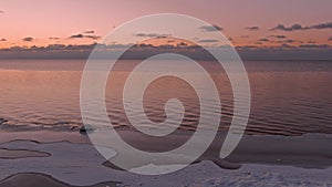 Sunset in a calm sea with frozen seashore.