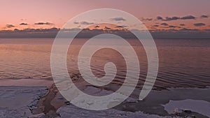 Sunset in a calm sea with frozen seashore.