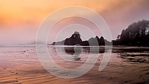 Sunset causing an Orange Glow over the Fog hanging over the rocky shore between Cox Bay and Chesterman Beach