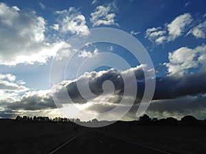 Sunset through the clouds along a country road