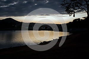 Sunset between clouds at dusk with golden sky, with reflection in pond.