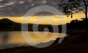 Sunset between clouds at dusk with golden sky, with reflection in pond.