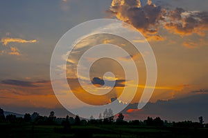 Sunset, clouds lit by the orange rays of the sun against the blue evening sky. Colorful summer landscape