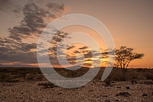 Sunset through the clouds over an arid desert landscape of sand