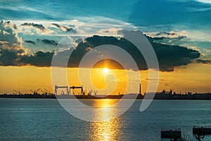 Sunset in clouds over river and shipbuilding factory